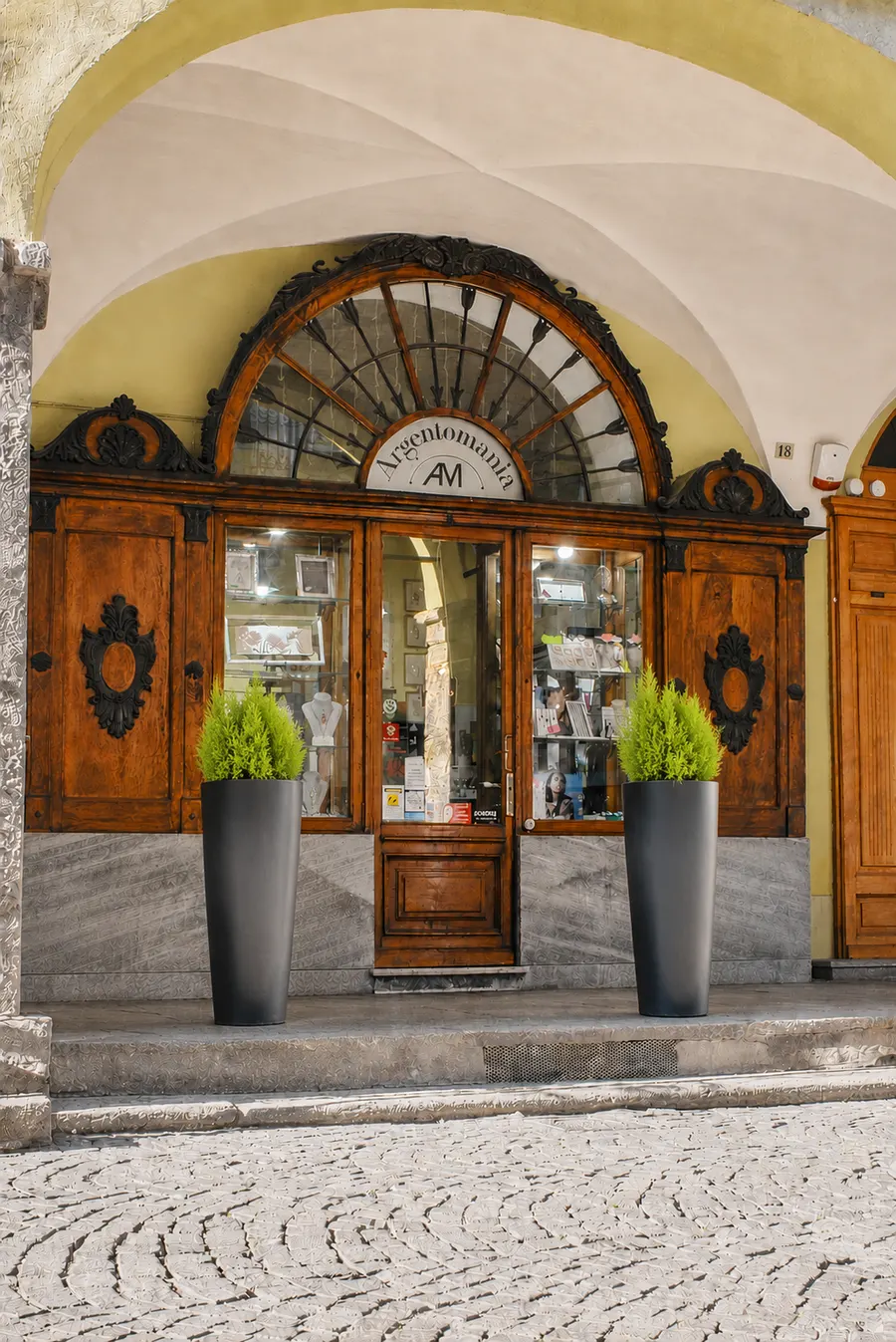 Ingresso della gioielleria Argentomania nel Palazzo Galup a Pinerolo: portone in legno antico con decorazioni in ferro battuto, sotto i portici del centro storico pinerolese